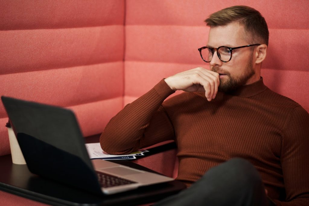 pexels-photo-5918195 Concentrated businessman wearing eyeglasses working on a laptop indoors.